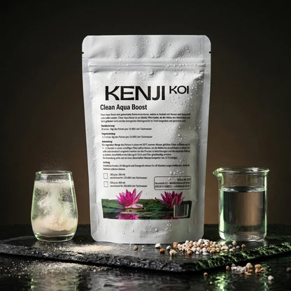 Kenji Koi Clean Aqua Boost 320g auf schwarzem Naturschiefer mit sich auflösendem Bakterienkonzentrat im Glas und klarem Wasser – Filterstarterbakterien mit Doppelwirkung für Filteraktivierung und Wasserqualität