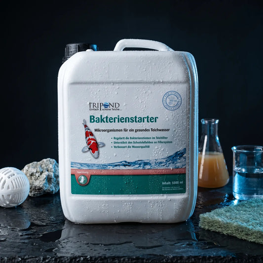 Tripond Bakterienstarter Flüssigkonzentrat auf schwarzem Naturschiefer mit Bioball, Zeolith-Stein und Filtermatte als Symbol für Universalkompatibilität – flüssige Filterbakterien für alle Teichfiltertypen